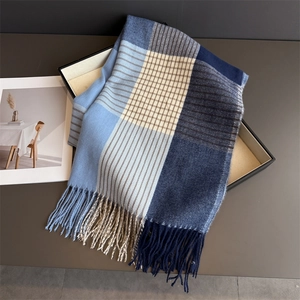 Detail view of plaid cashmere scarf featuring soft fringes and blue grid patterns