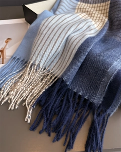 Detail of soft winter plaid scarf showing knit texture and navy blue tassel fringe