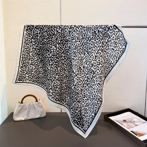 Elegant leopard print square scarf in black and white hanging next to a stylish handbag