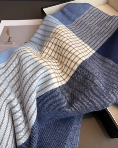 Close-up of a thick plaid scarf with blue and beige grid patterns in a gift box