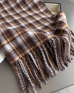 Gros plan sur le motif à carreaux marron et beige et les franges de l'écharpe