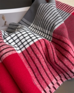 Close-up of soft plaid knit scarf texture with classic red, grey, and white checkered pattern