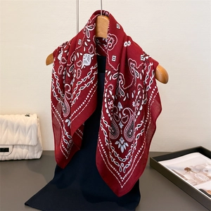 Gros plan du foulard en coton lin à motif cachemire bordeaux sur un cintre en bois