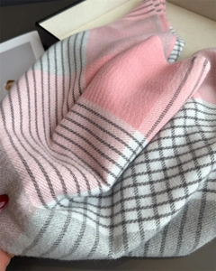 Close-up of pink and grey plaid scarf showing soft fabric texture and fringe details