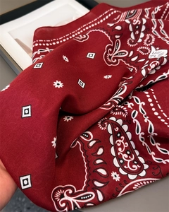 Gros plan d'un foulard carré rouge foncé à motif paisley montrant le tissu en sergé