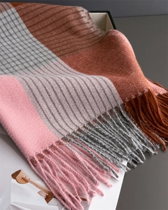 Detailed close-up of soft plaid scarf fabric with pink and grey blocks and fringe