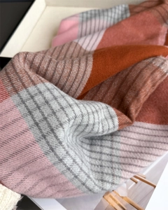 Close-up of soft plaid scarf fabric showing orange and pink twill weave texture
