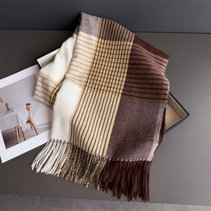 Detailed view of the thick fringe and plaid texture of a warm cashmere-feel winter scarf