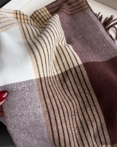 Close-up of winter plaid scarf with brown tassels and soft faux cashmere texture