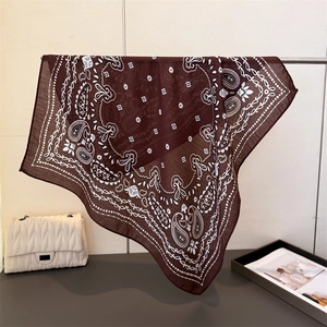 Foulard en coton marron foncé à motif paisley suspendu sur un support métallique
