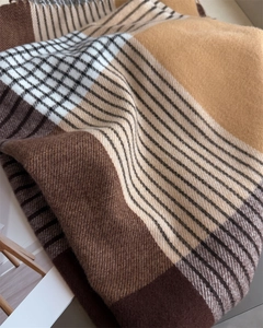 Close-up of soft brushed texture and fringe detail on a classic plaid winter scarf