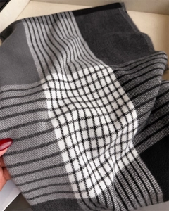 Close-up of winter plaid scarf texture showing soft grey and black checked knit fabric