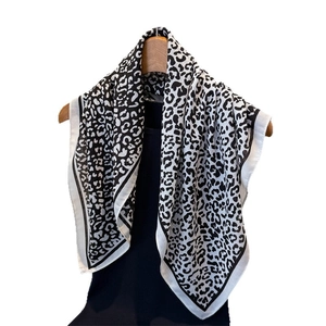 Fashionable leopard print square scarf in black and white hanging on a wooden hanger