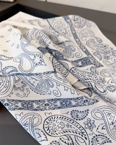 Detailed close-up of navy blue paisley pattern on ivory white silk-textured scarf fabric