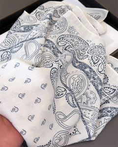Detail of white cotton linen scarf featuring classic navy paisley patterns and soft texture
