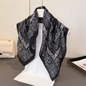 Elegant paisley print square scarf in black and white worn on a white blouse mannequin
