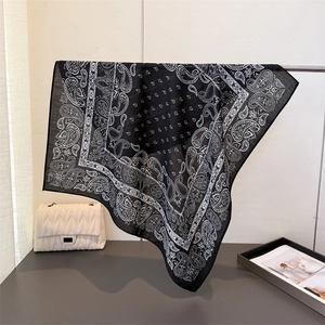 Detail of black and white paisley cotton-linen scarf draped on a metal display stand
