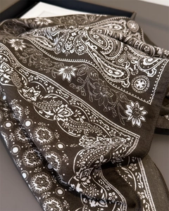 Detailed view of dark brown paisley silk scarf with intricate floral patterns and soft texture
