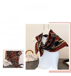 Détail d'un foulard carré vintage avec motifs de calèche et chaînes en rouge et noir