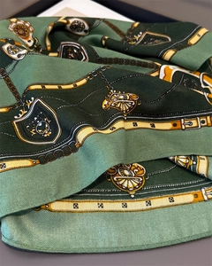 Détail d'un foulard en soie vert avec motifs de chaînes équestres et boucles de ceinture