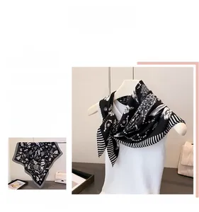 Detail view of monochrome silk-feel scarf with elegant chevron and dahlia patterns