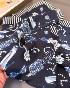 Detailed view of navy blue herringbone scarf featuring white floral and pearl chain patterns