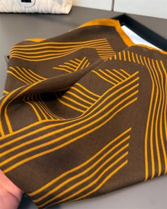 Gros plan du foulard en soie à motifs géométriques aux tons marron et jaune élégants