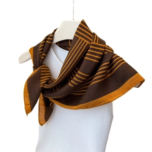 Écharpe à motifs géométriques marron et jaune portée sur un débardeur blanc