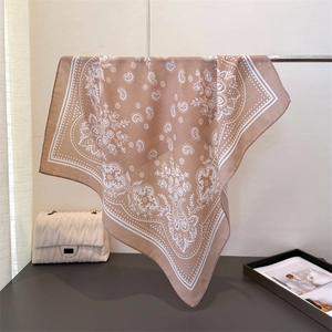 Detailansicht eines braunen Halstuchs mit Paisley-Muster an einer weißen Handtasche