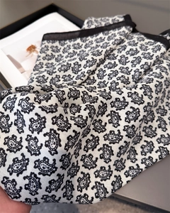 Détail du motif paisley sur tissu blanc avec bordure noire et texture sergé élégante