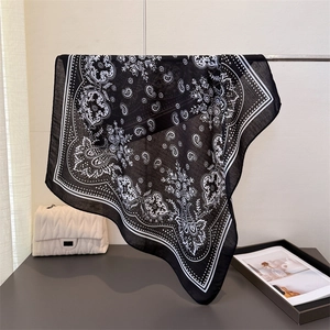 Detail eines eleganten schwarz-weißen Seidentuchs mit Paisleymuster an Metallstange