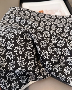 Vue détaillée du foulard en soie à motif paisley noir avec texture sergée et bord blanc
