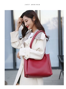 Detail of a dark red leather tote bag worn by a model in a beige trench coat outdoors