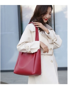 Deep red leather tote bag styled with a beige trench coat against a modern glass building