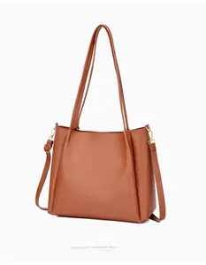 Detail view of a caramel faux leather tote bag showing fine texture and golden hardware