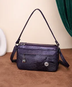 Dettaglio borsa a tracolla viola motivo coccodrillo con ciondoli metallici e zip doppie