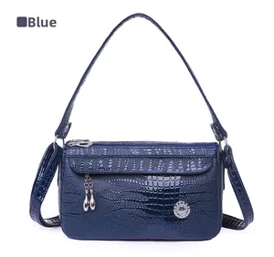 Dettaglio borsa blu motivo coccodrillo con ciondolo in metallo e logo con brillanti d'acqua