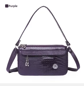 Dettaglio della borsa viola con trama a coccodrillo e fibbia decorativa in metallo lucido