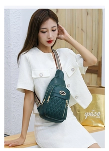 Detail of dark green quilted leather chest bag with gold zipper and striped strap
