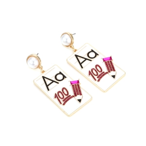 Détail de boucles d'oreilles thème école avec lettre Aa, chiffre 100 et petit crayon rose