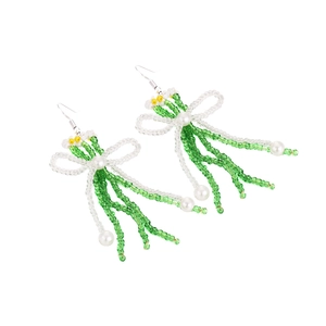 Détails de boucles d'oreilles artisanales en perles avec nœud vert et fleurs