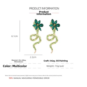 Detail of gold snake earrings with green rhinestones showing craftsmanship and size