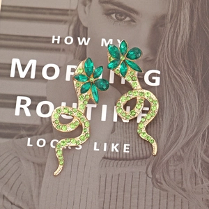 Elegant gold snake earrings with green crystal flowers in a stylish flat lay display