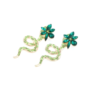Snake shape gold earrings with colorful rhinestones and green crystals on white background