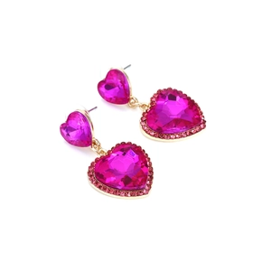 Dettaglio macro di orecchini a cuore in cristallo rosa con base dorata e strass pavé