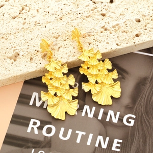 Retro multi-layer golden ginkgo leaf dangle earrings on textured beige stone