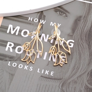 Boucles d'oreilles tulipes évidées vintage dorées sur un magazine pour un look élégant