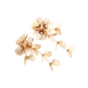 Detailed macro view of large golden metal floral earrings with crystal centers and mesh petals