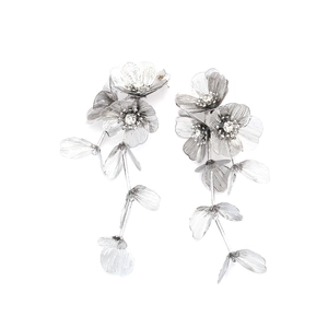 Macro shot of silver metal flower tassel earrings with filigree petals and crystal centers