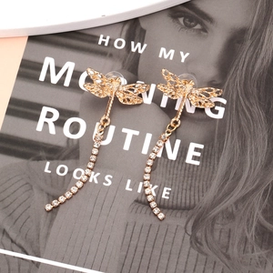 Elegant gold dragonfly drop earrings with rhinestone tassels on a fashion magazine background